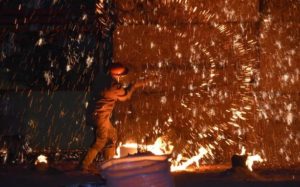 image of sparks flying as artist throws molten metal on wall