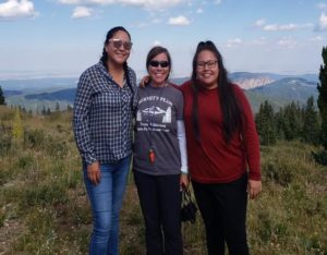 Photo of three students atop Elk Mountain with valley in the background.
