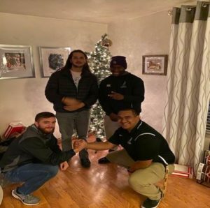 Gathering of students in front of a holiday-lit tree.