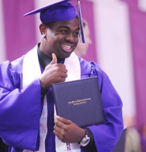 photo of student holding diploma and giving a thumbs up sign
