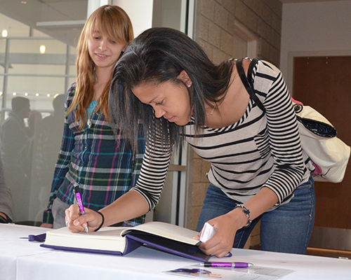 Graduates signing time capsule book