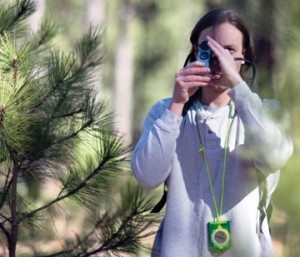 Photo of student in the woods with a measuing device