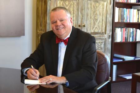 Highlands University President Sam Minner writes a check Dec. 4 for a $1,000 personal donation to the Highlands Foundations’s campaign to support more high-impact practices for student success. Photo: Margaret McKinney/Highlands University