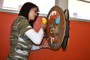 Photo: Margaret McKinney/Highlands University Media arts Bachelor of Fine Arts candidate Ivana Moose Vidal uses a drill to install signage she designed for her branding project for Chilly Chili ice cream. Her project is part of the media arts Spring Exhibit. 