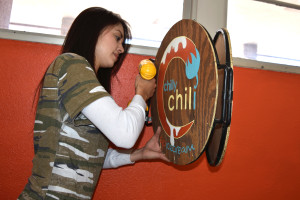 Photo: Margaret McKinney/Highlands University Media arts Bachelor of Fine Arts candidate Ivana Moose Vidal uses a drill to install signage she designed for her branding project for Chilly Chili ice cream. Her project is part of the media arts Spring Exhibit.