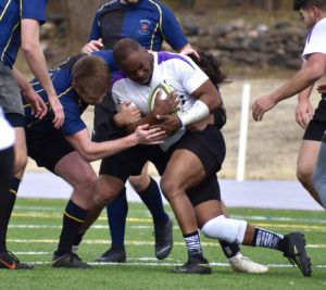 Photo of Justin Stallworth being tackled but keeping the ball. during rugby game