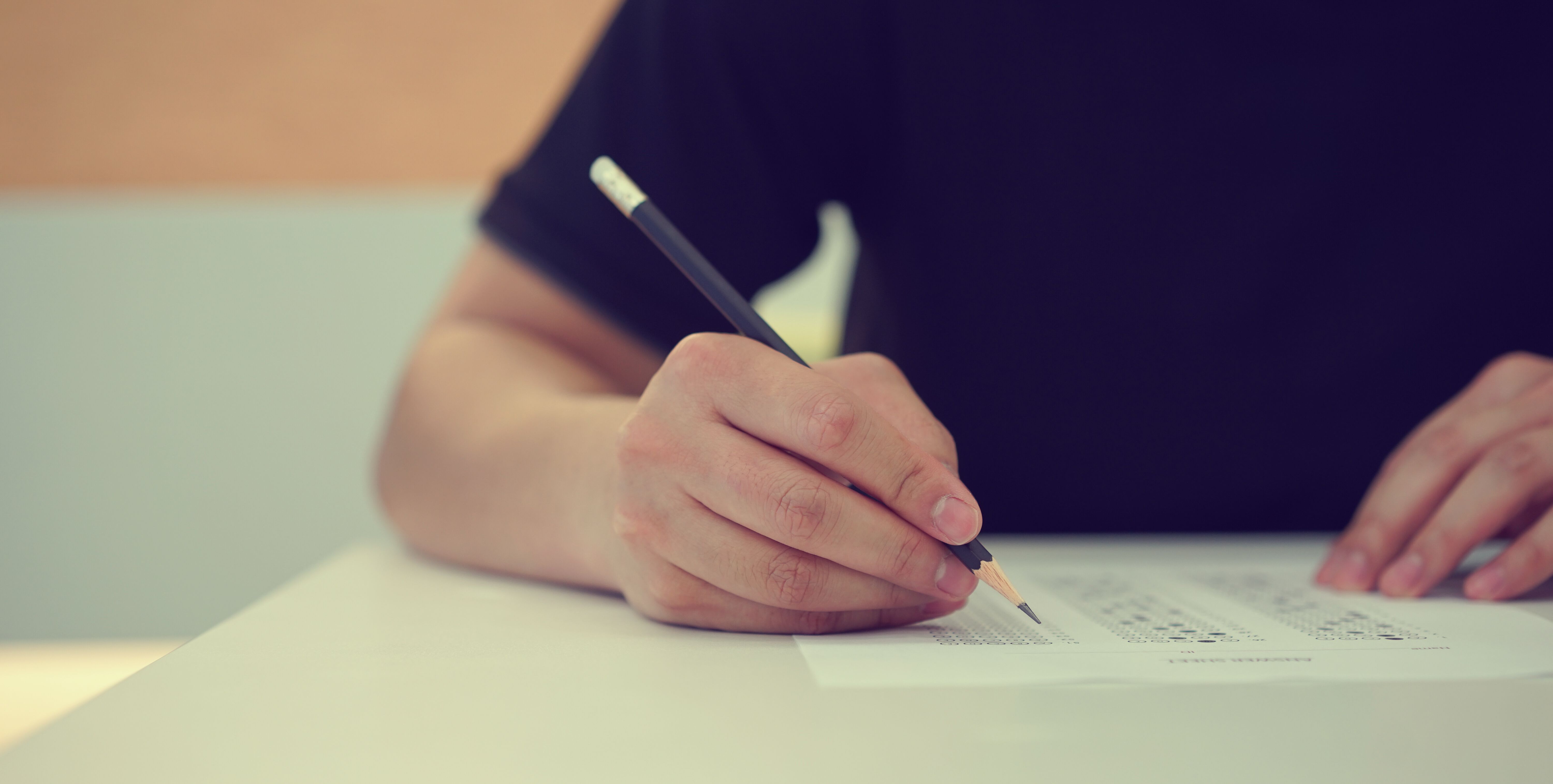 Image of student's hand filling out exam paper