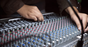Closeup of hands on electronic music mixer