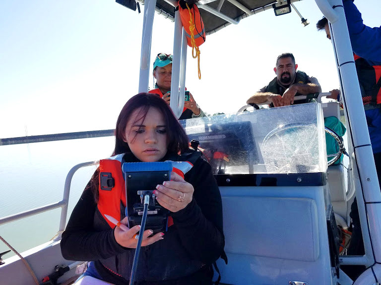 Photo of Nikita Tenorio, a New Mexico Highlands University conservation management senior from Anton Chico, New Mexico using a multiparameter water quality instrument at Storrie Lake..