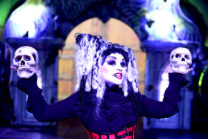 Photo of happy performer in costume, holding two skulls