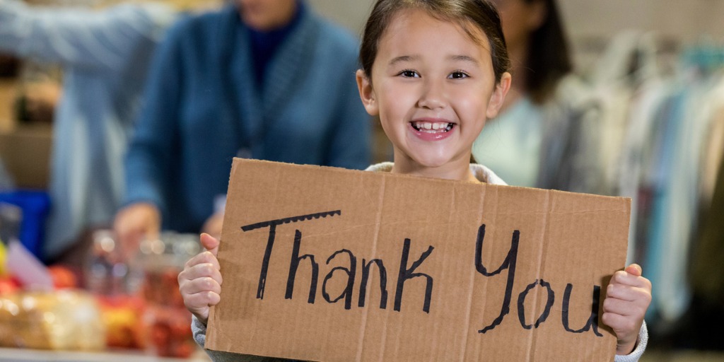 Photo of smiling child holding large Thank You sign.