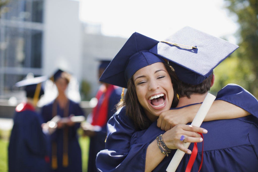 Smiling graduates hugging outdoors New Mexico Highlands University