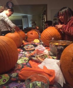 Photo of people carving pumpkins at a long table.