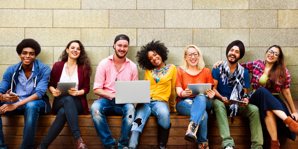 image of a group of happy students sitting on a wall.