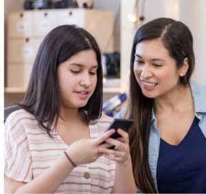 Two women look at a cell phone screen together