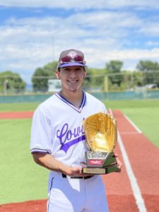 Estevan De La O poses in his white and purple Cowboys baseball uniform and holds his Gold Glove trophy. 