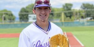 Estevan De La O poses in his white and purple Cowboys baseball uniform and holds his Gold Glove trophy.