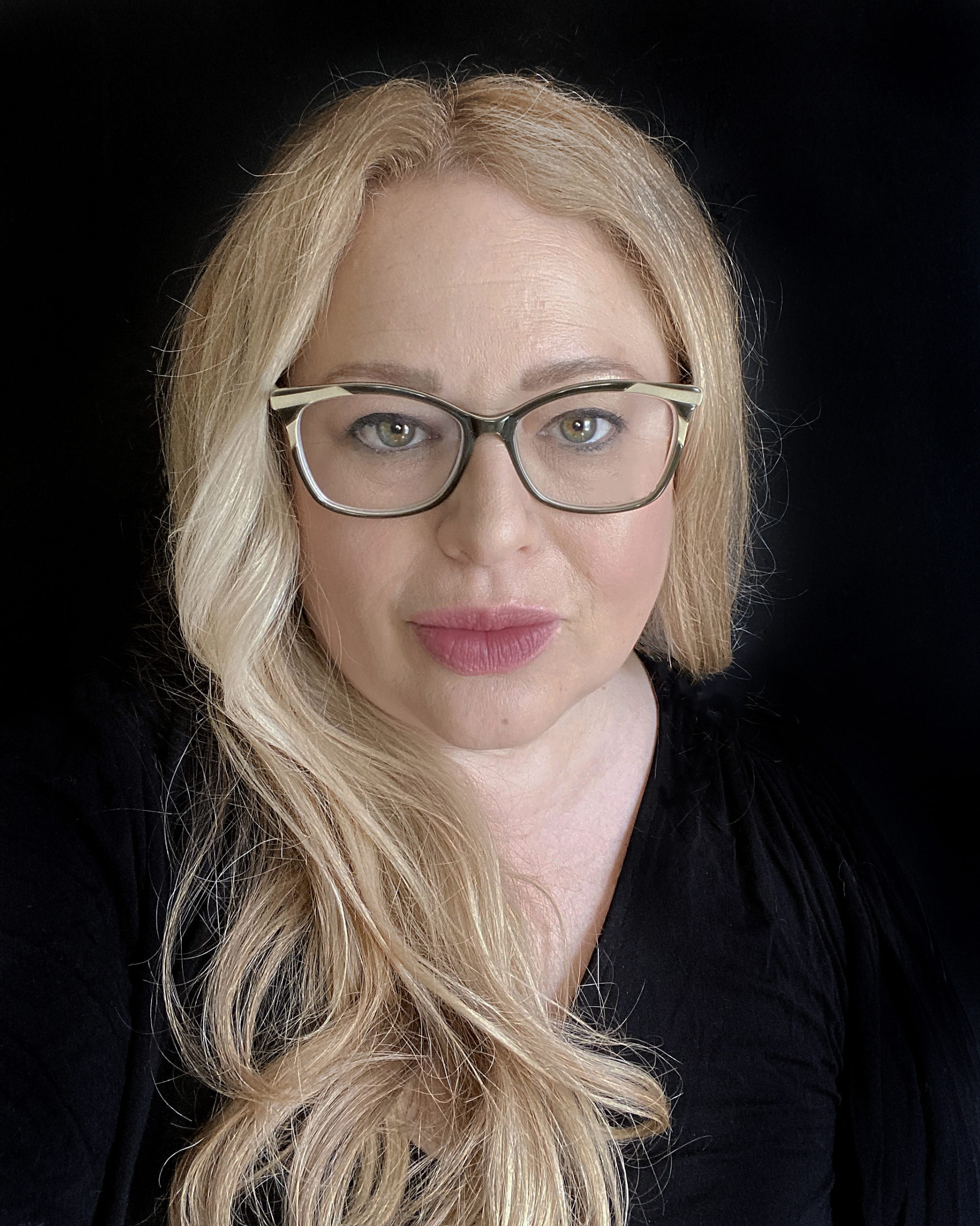Headshot of Traer Scott, a blonde woman with long hair and glasses