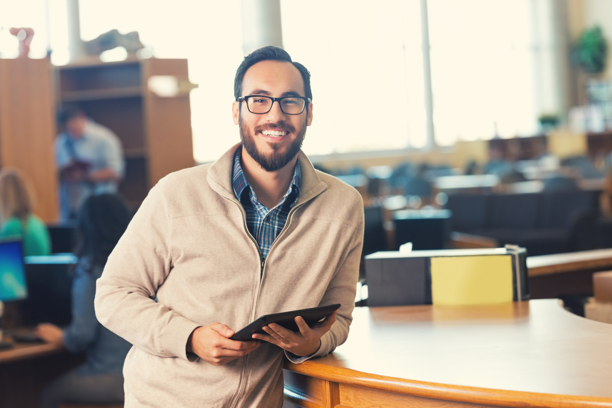 Smiling teacher leaning on a library counter