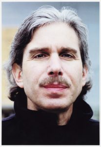 Headshot of filmmaker David Sutherland, white man with mustache and grey hair