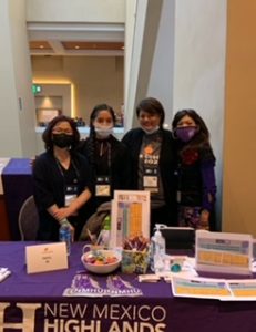 NMHU professors pose in masks at a table at the 2021 La Cosecha conference