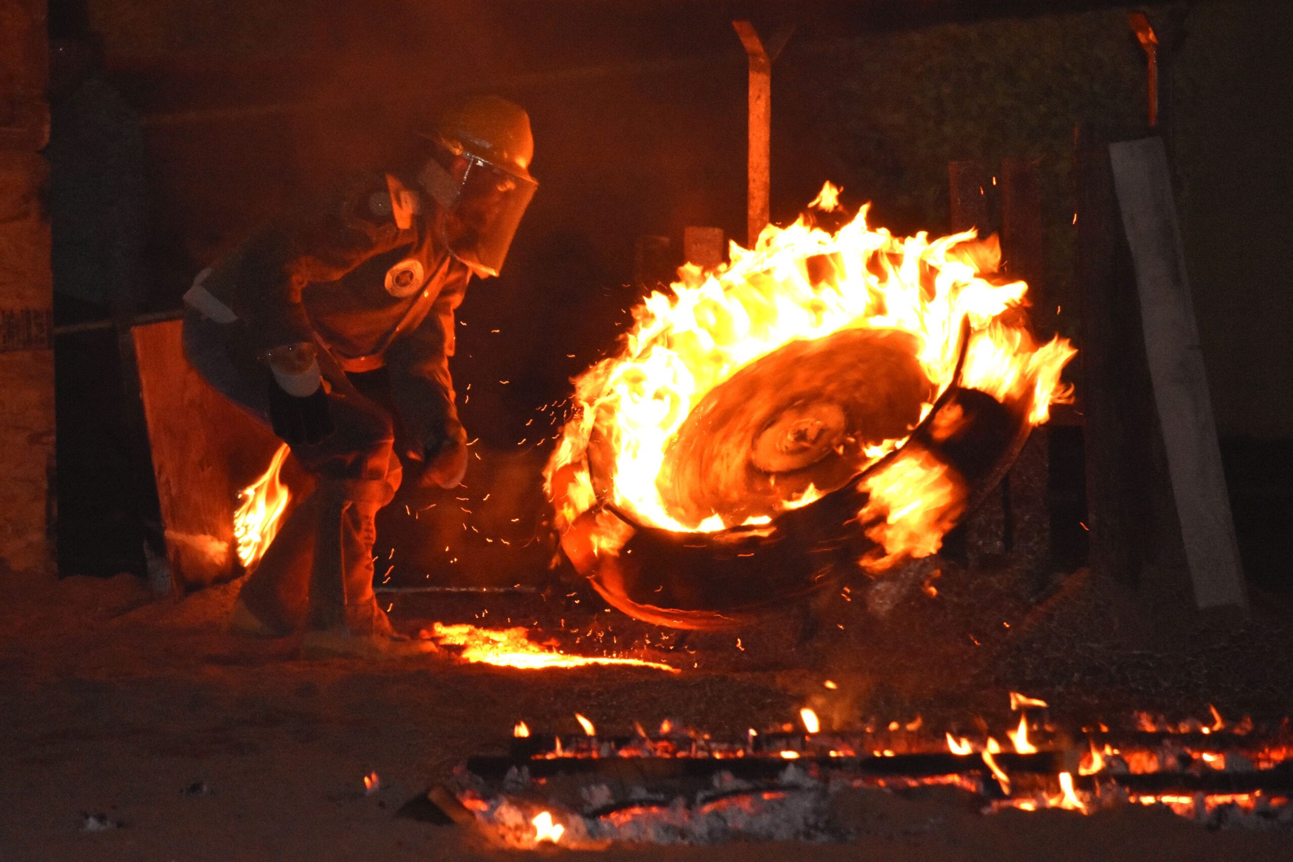 Image of one person working on a hot metal sculpture