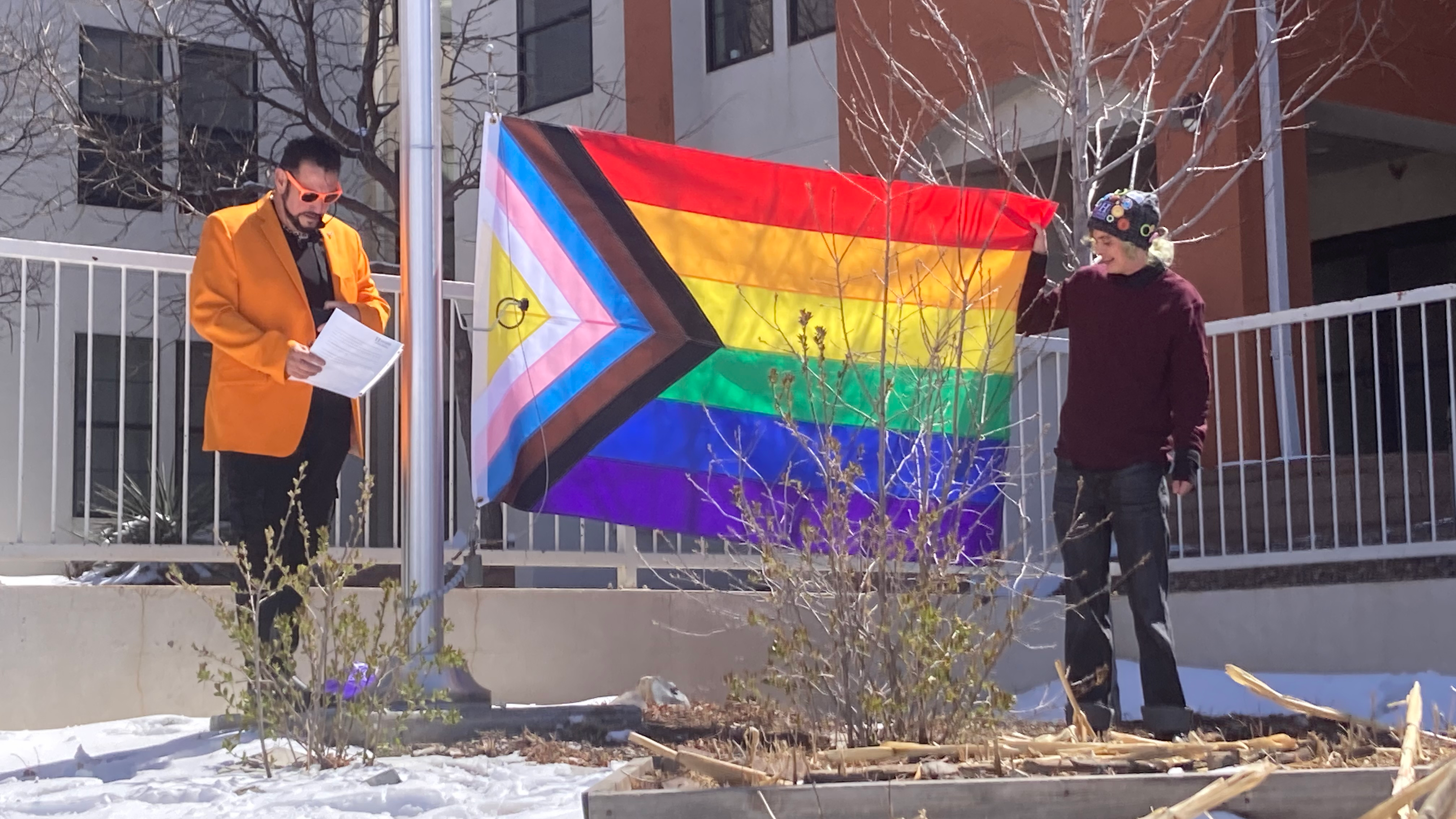 Image of two people preparing to raise the Pride Flag at NMHU.