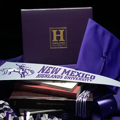 Image of a Highlands University diploma cover, graduation cap, and pennant.