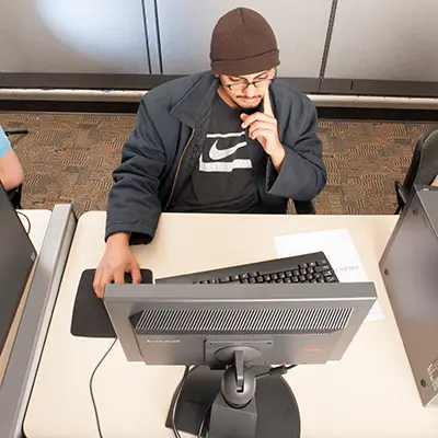 A student studying at a computer in a computer lab.