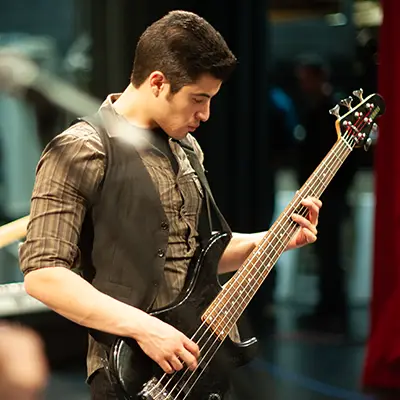 A male student playing a guitar in a studio