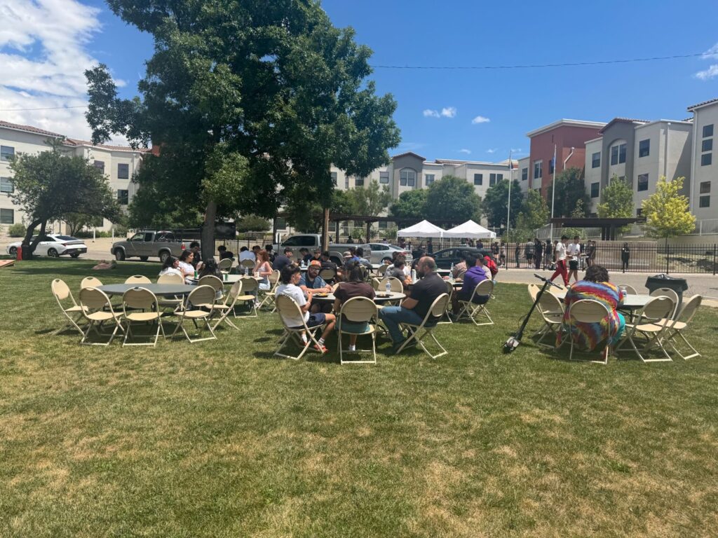 People sitting at tables outside taking a break from move in day.