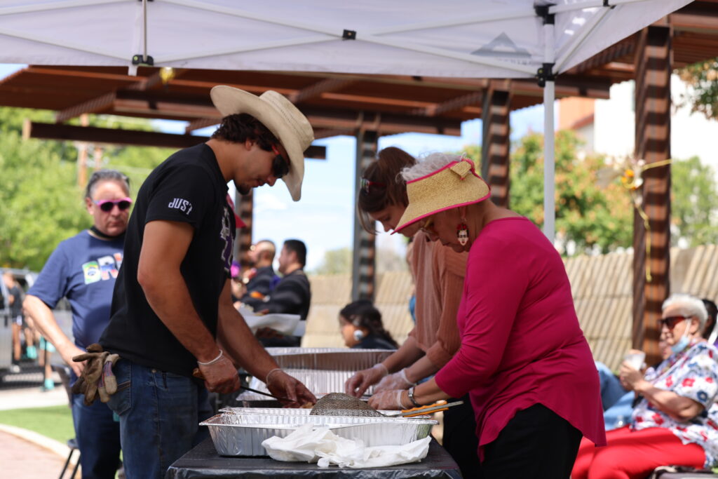 Image of people filling plates with food at an outside venue.