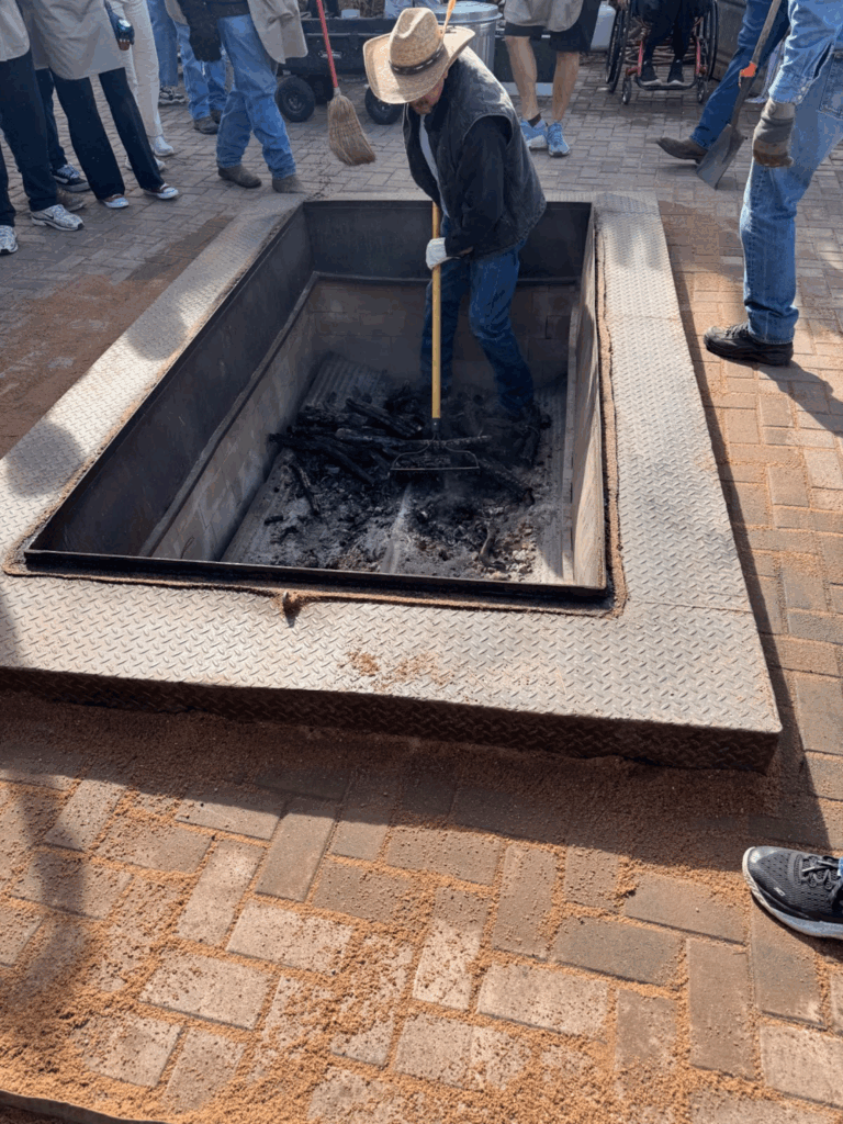 An image of a man in a cowboy hat preparing the Matanza firepit