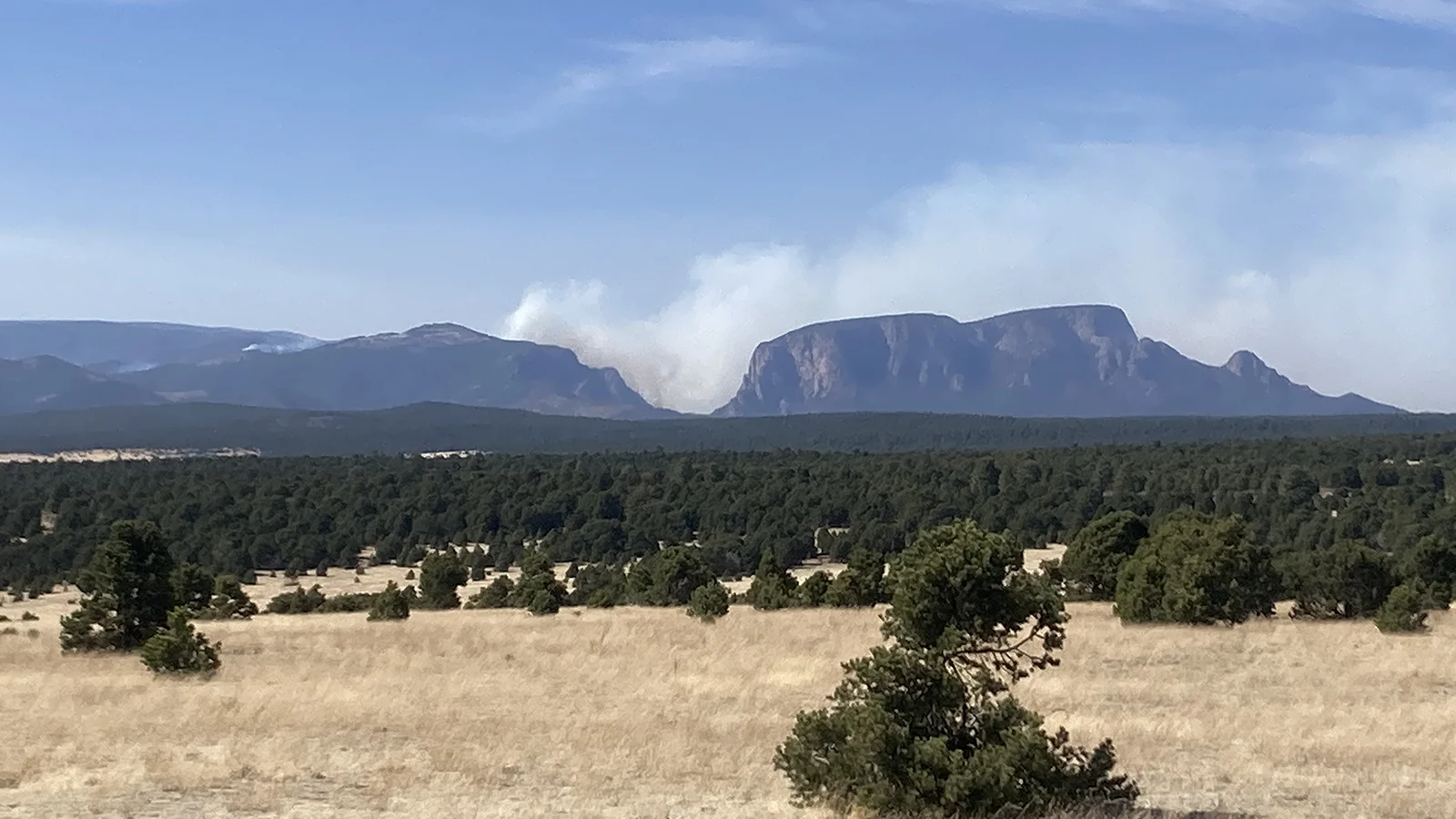 Image of smoke from the hermit's Peak forest fire rising in a valley between two mountains.