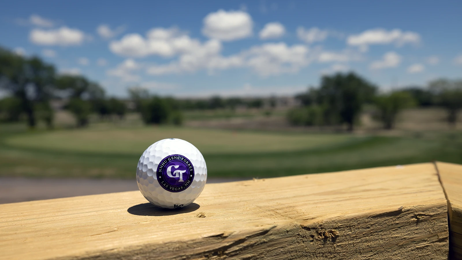 Close up image of a Gene Torres course golf ball with the course seen in the background.