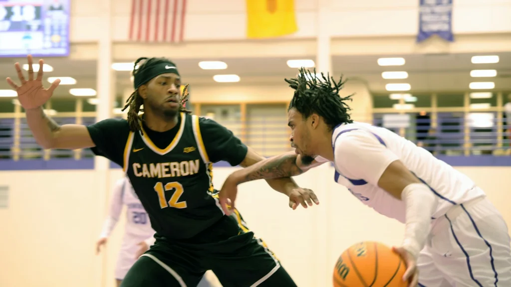 NMHU men's basketball player driving to the hoop in a game against Cameron University