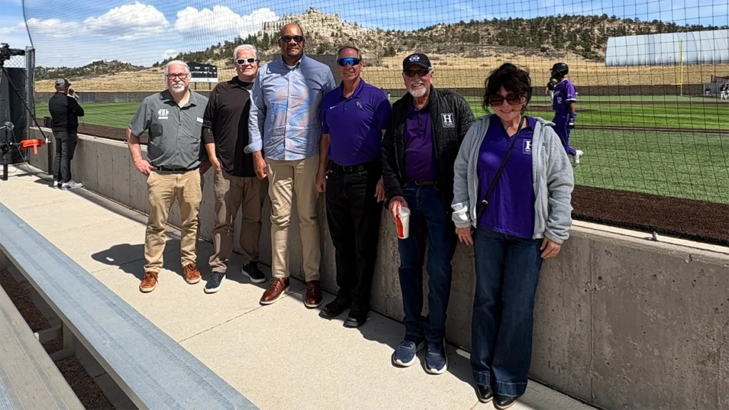 President Woolf and a group standing in front of a baseball field in Colorado Springs.