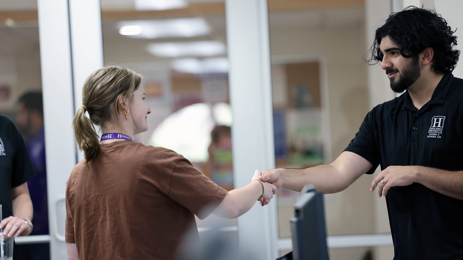 A student and staff member are shaking hands during a discussion.